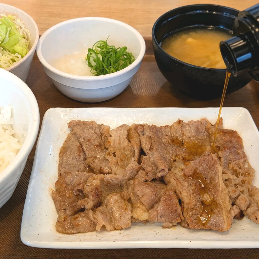 松屋『カルビ焼肉定食』喫食ポストの画像。甘口ダレを別添の小瓶から焼肉の上に注ぐ瞬間