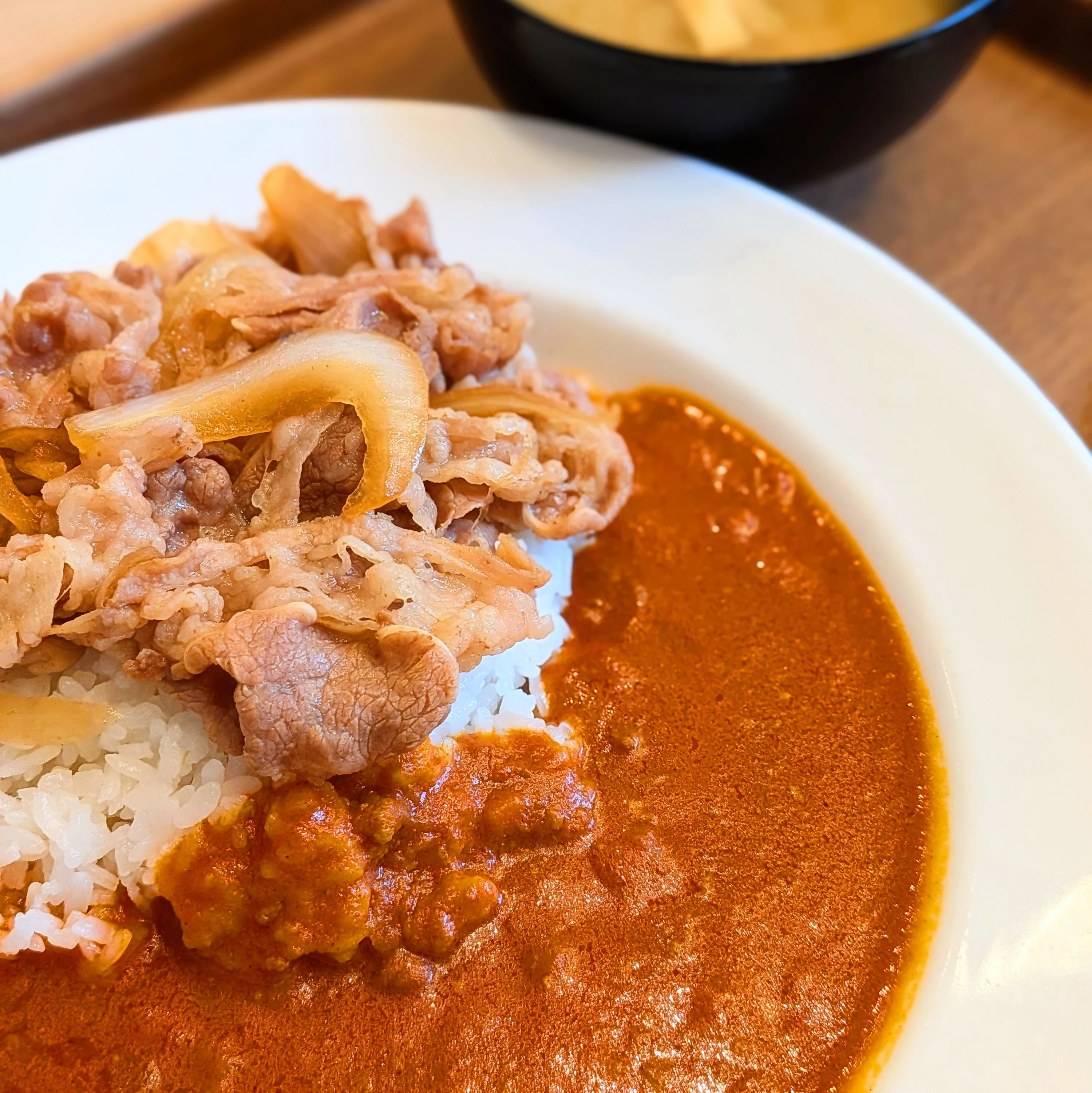 松屋『ネオトマトカレギュウ』喫食ポストの画像。白い丸皿の左にライスと焼き目のついた牛肉・玉ねぎ、右側に明るいオレンジ色のトマトカレーソースを分離盛りした構図