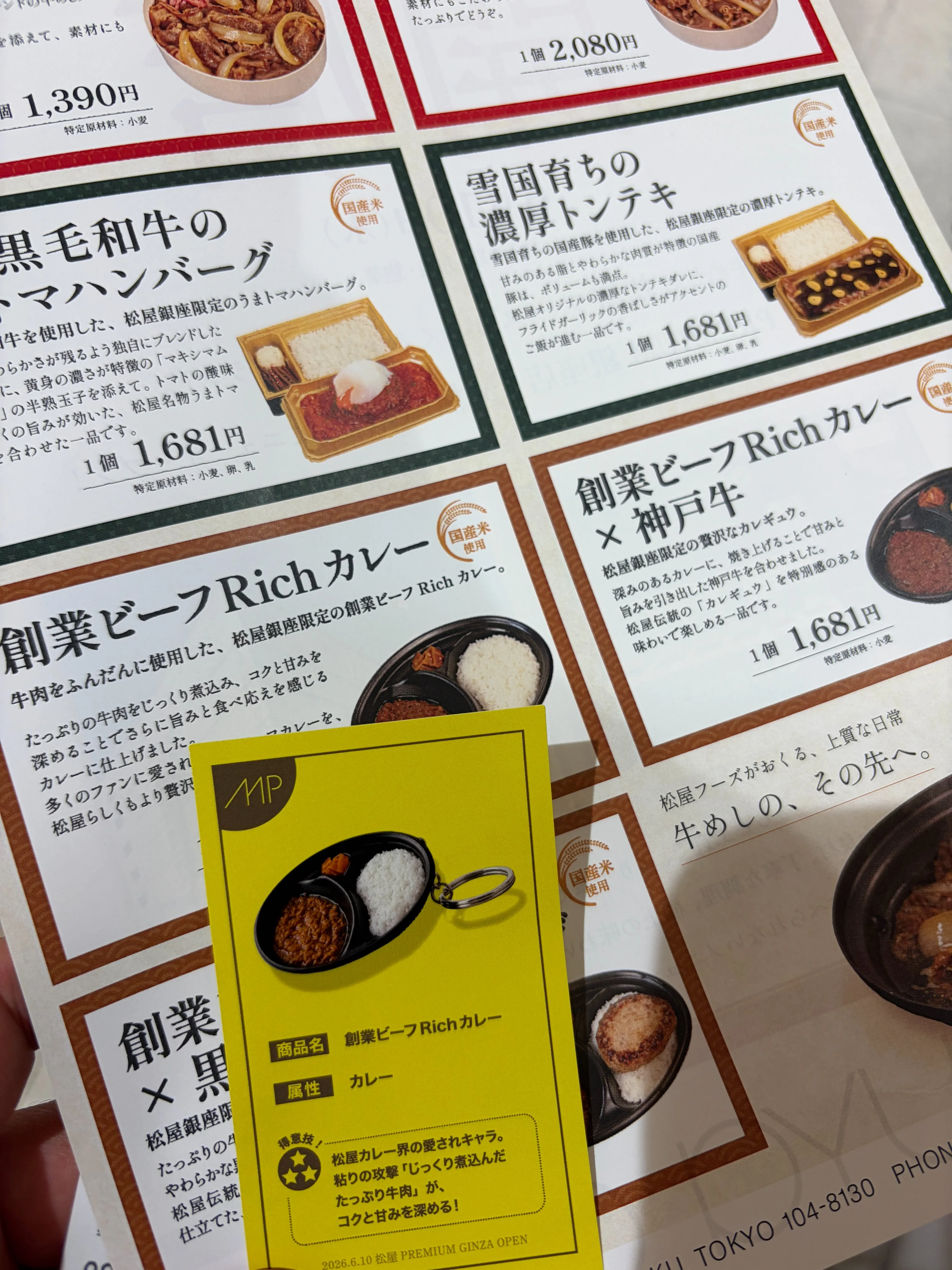 松屋PREMIUM 銀座店の商品リーフレットと限定オリジナルカード。リーフレット中央に黄色のカードが置かれ、カードには『MP』ロゴ、商品キャラクター風イラスト、商品名・属性・ステータス文が記載される